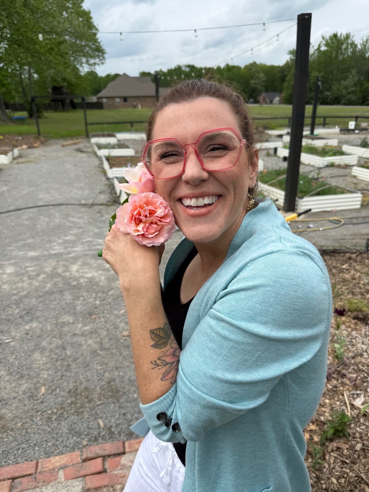Lauren Faulk, owner of Taylor's Field, smiling and holding a pink rose at the farm